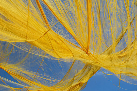 Yellow curtain dancing in the wind against blue sky