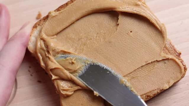 Woman preparing toast with delicious peanut butter 