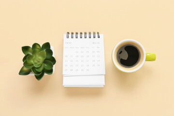 Flip paper calendar for March with cup of coffee and houseplant on beige background