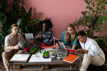 Diverse group of international students working on the urban project of modern city with renewable energy source, green areas. Concept of ecology, environment protection, waste recycling, technology