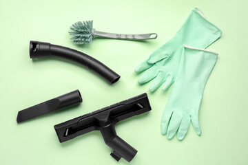 Vacuum cleaner attachments with brush and gloves on green background