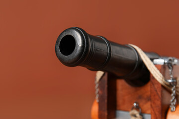 Toy model of cannon on brown background, closeup