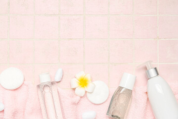 Obraz na płótnie Canvas Towel with micellar water, cotton pads, buds, balls and flower on pink tile background