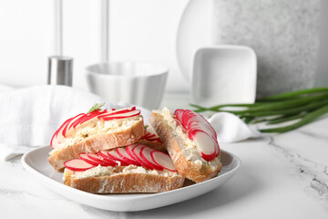 Plate with delicious radish bruschettas on white tiled table