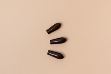 Group of brown rectal suppositories for anal or vaginal use on beige isolated background. Pills for alternative medicine, lowering temperature, hemorrhoids and wellness