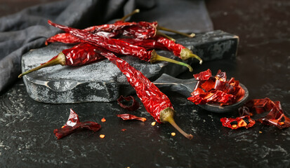 Board with dry hot chili peppers on dark background