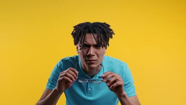 African man takes off glasses,squinting because can't see anything.Poor eyesight