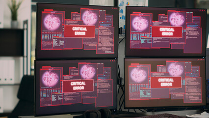 Multiple computers showing hacking alert and security breach, server system being hacked. Monitors showing critical error message flashing on screen and malware threat warning.