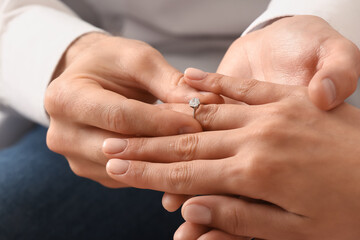 Man putting engagement ring on woman's finger, closeup