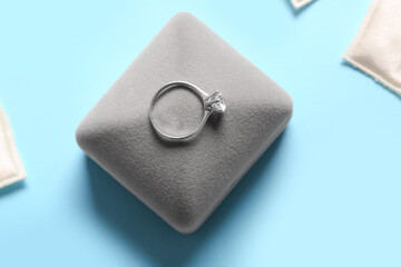 Box with engagement ring on blue background