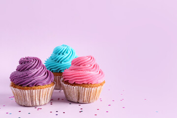 Tasty colorful cupcakes on purple background