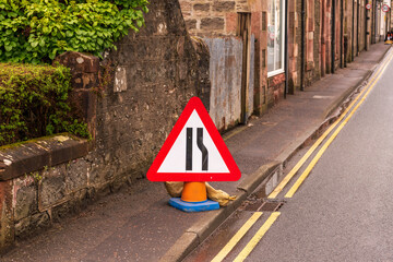 Road Narrows: Temporay signage alerts drivers to a constriction in the road ahead on the quaint...
