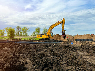big yellow excavator works in the summer in the field