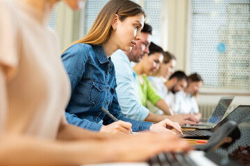 Fototapeta premium Woman sitting in classroom during lecture in university and using laptop.