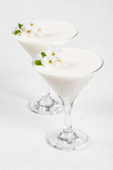 Vanilla cream jelly, Panna Cotta, decorated with small white flowers, in a martini glass. White background