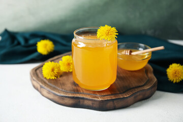 Jar and bowl with dandelion honey on white table
