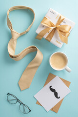 Make Father's Day unforgettable with an elegant gesture. Top vertical view of silk necktie, spectacles, postal with mustaches, gift box, envelope, coffee cup, men's accessories on blue background