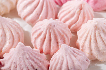 Pink meringue cookies with berry flavor on baking parchment