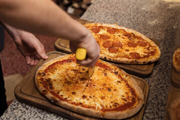 Close up of anonimous pizza chef slicing appetising pizza with cutter wheel in order to be served...