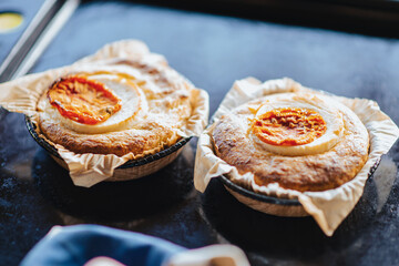 casserole with cheese and tomato. Two servings of round casseroles on a dark background.