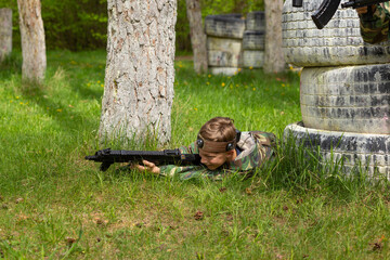 Boy weared in camouflage playing laser tag in special forest playground.
