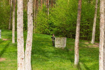Boy weared in camouflage playing laser tag in special forest playground.