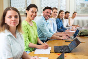 Obraz premium Asian woman university student sitting at table in class room, looking at camera and smiling.