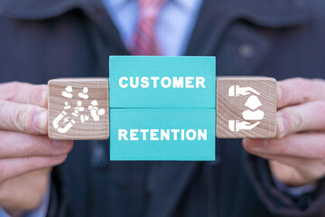 Man holding colorful blocks with icons and inscription: CUSTOMER RETENTION. Concept of customer...