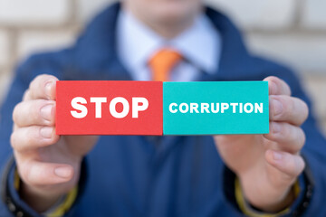 Businessman or politician holding colorful blocks with inscription: STOP CORRUPTION. Concept of stop bribery and corruption. Illegal corrupt activity. Anti-corruption. AML. - obrazy, fototapety, plakaty