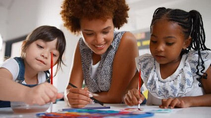 Close up of female elementary school teacher with pupils in art class  - shot in slow motion - Powered by Adobe