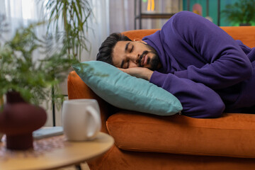 Tired indian man lying down in bed taking a rest. Carefree young hindu guy napping, falling asleep...