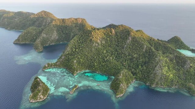 Evening sunlight illuminates the dramatic limestone islands that rise from Raja Ampat's seascape. This remote part of Indonesia is known for its incredibly high marine biodiversity.
