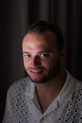 Obraz premium Posing against a dark curtain, a Middle Eastern man expresses a slight smile and handome look.