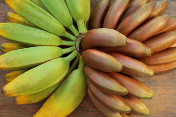 Different sorts of bananas on wooden table, top view