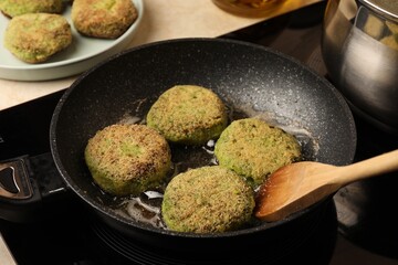 Cooking vegan cutlets in frying pan on stove, closeup