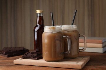 Delicious iced coffee with chocolate syrup on wooden table
