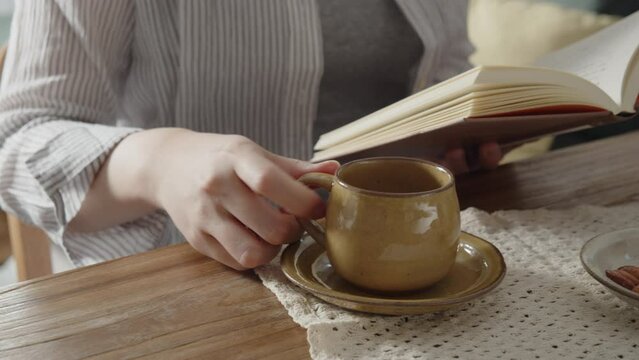 A Japanese woman drinks a cup of coffee and reads the book. 02
