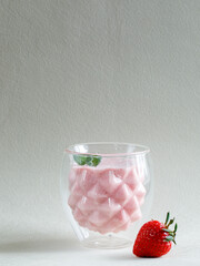 Healthy Strawberry Cream mousse in glass on a white wooden board with whole berry and mint leaves. Delisious summer dessert. Vertical