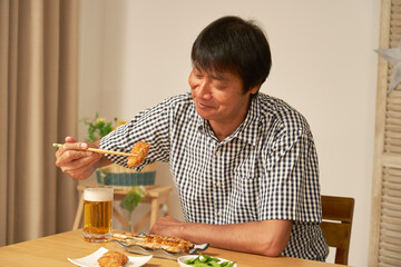 自宅で一人で晩酌をする中年男性