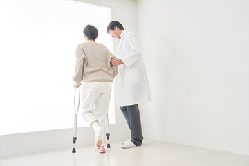 Obraz premium 医者と松葉杖を使って歩く中年女性