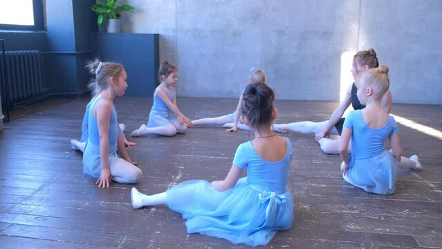 4k Group of teen girls practicing various dance moves with instructor. Kids learning ballet with experienced coach