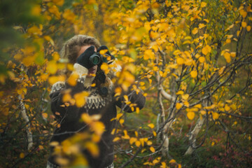 Caucasian woman birdwatching with binoculars autumn forest