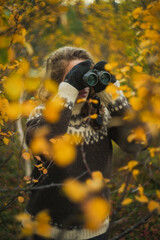 Caucasian woman birdwatching with binoculars autumn forest