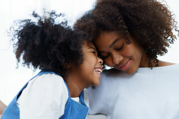 Lovely cute girl and mom embracing together, girl giving her mother a kiss and hug.