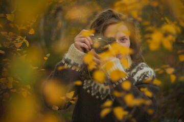 Caucasian female photographer using camera in yellow autumn forest