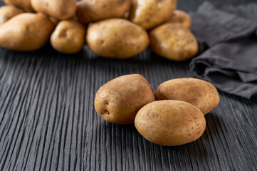 Raw yellow potatoes on a black  wooden table, selective focus.