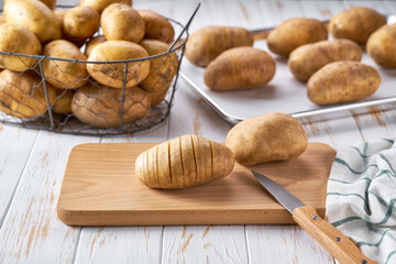 Traditional recipe Hasselback potatoes with thyme and salt on baking tray, preparation for baking.