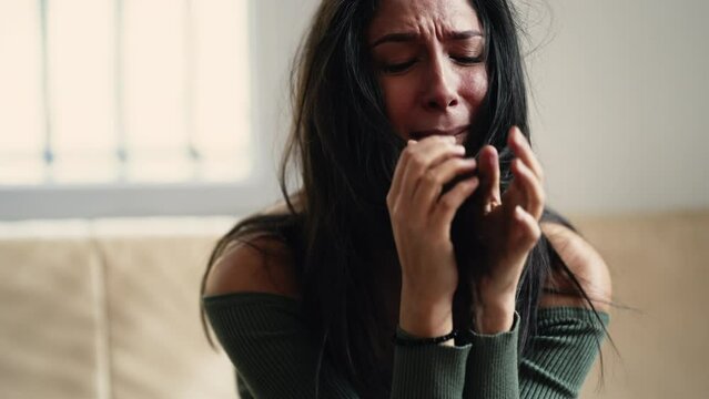 Distressed young woman overwhelmed with anxiety and sadness, feeling helpless and lost at home