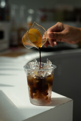 A cup of iced coffee with a clear plastic cup sits on a table in a cafe