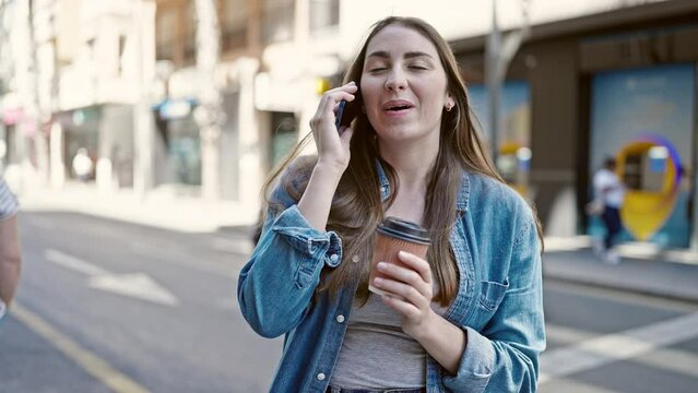 Young beautiful hispanic woman talking on smartphone drinking coffee at street